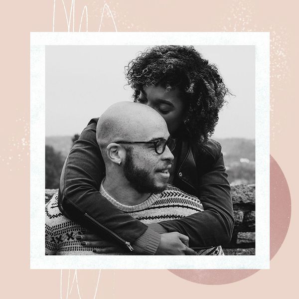 woman with curly hugging man with glasses who is looking away from the camera
