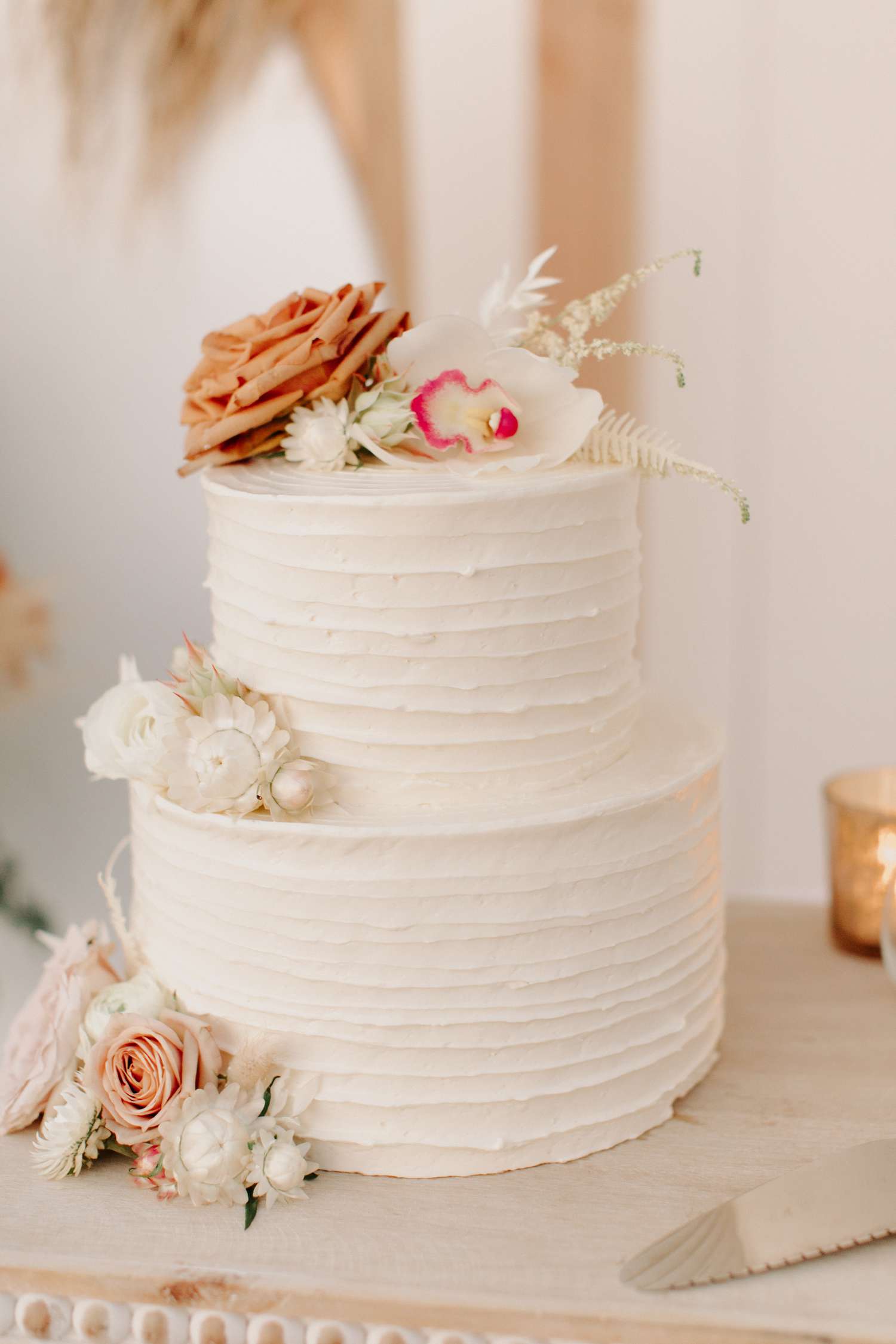 Two-tier buttercream cake with ruffle frosting and white and orange florals