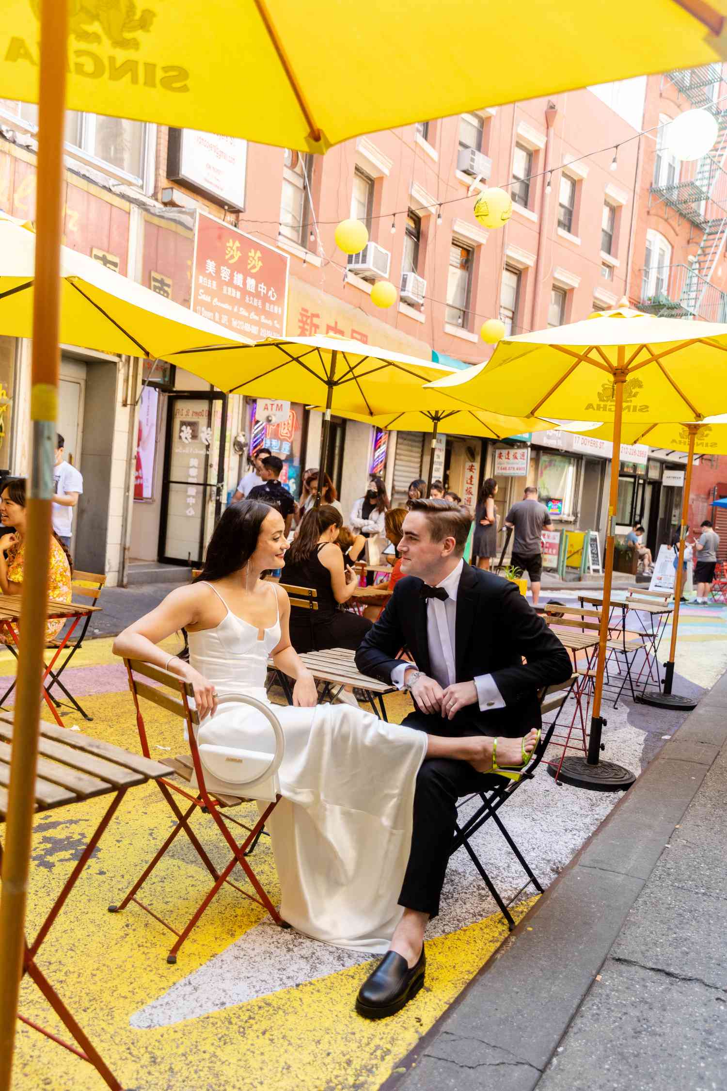 Bride and Groom Sit Outside on the Street in New York City Under Yellow Umbrellas