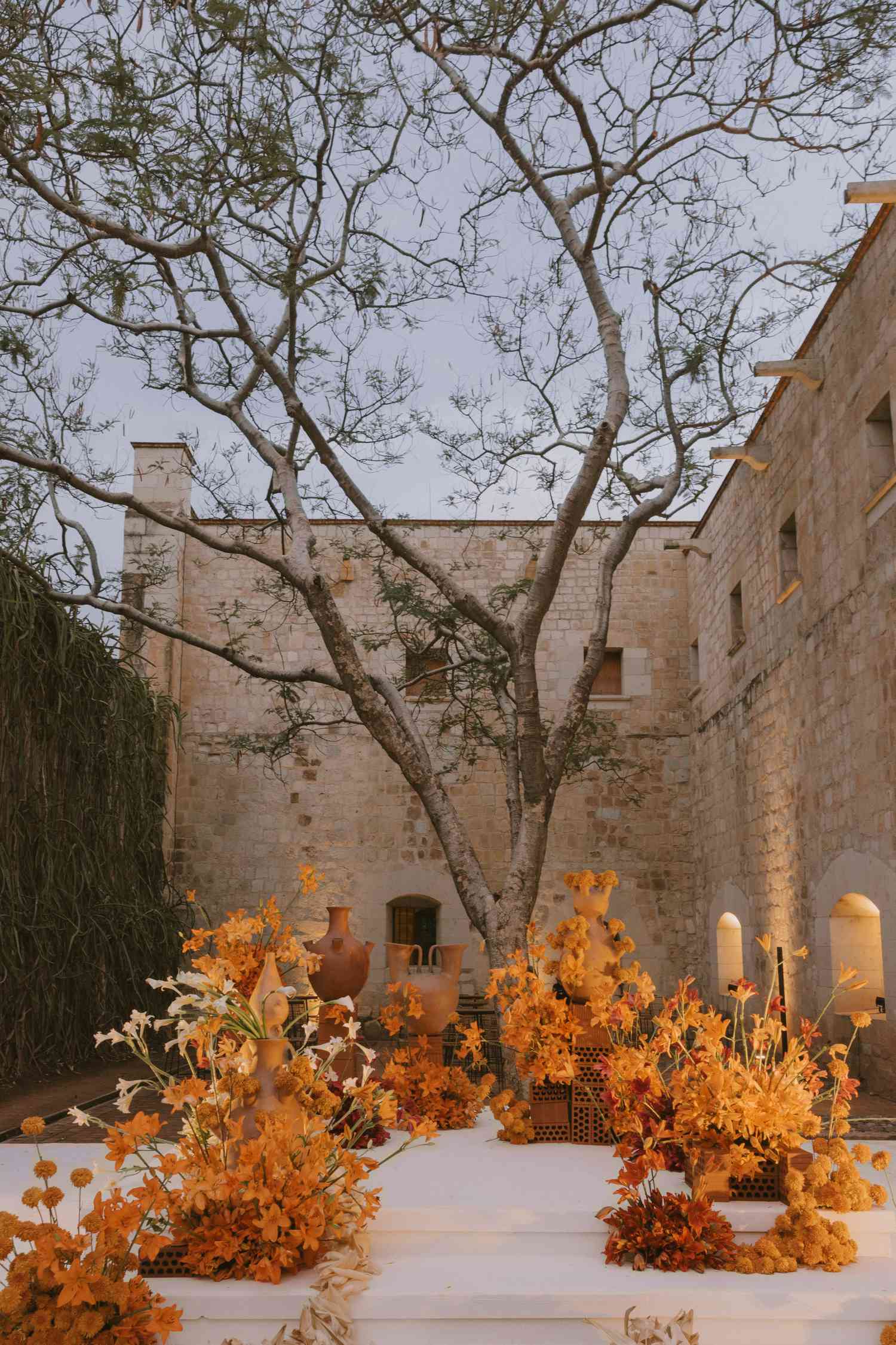 Evening Ceremony Setup With Orange Altar Arrangement of Flowers, Urns, and Leaves