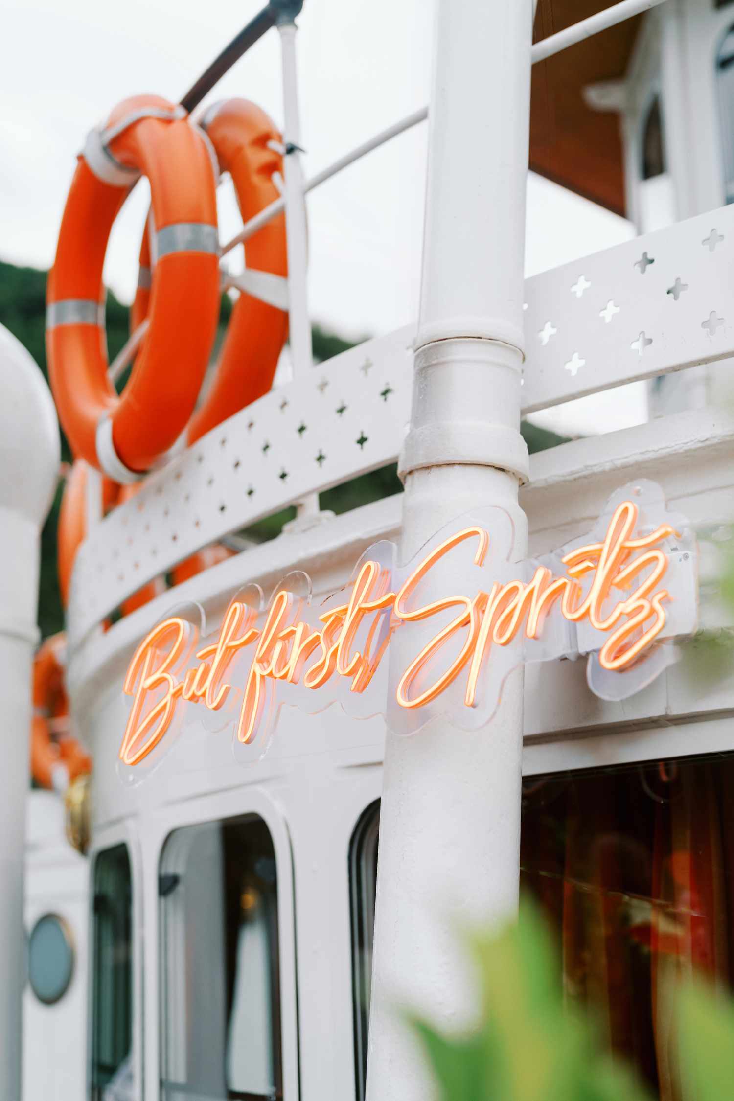Orange Neon Sign on a Boat That Says "But First, Spritz"