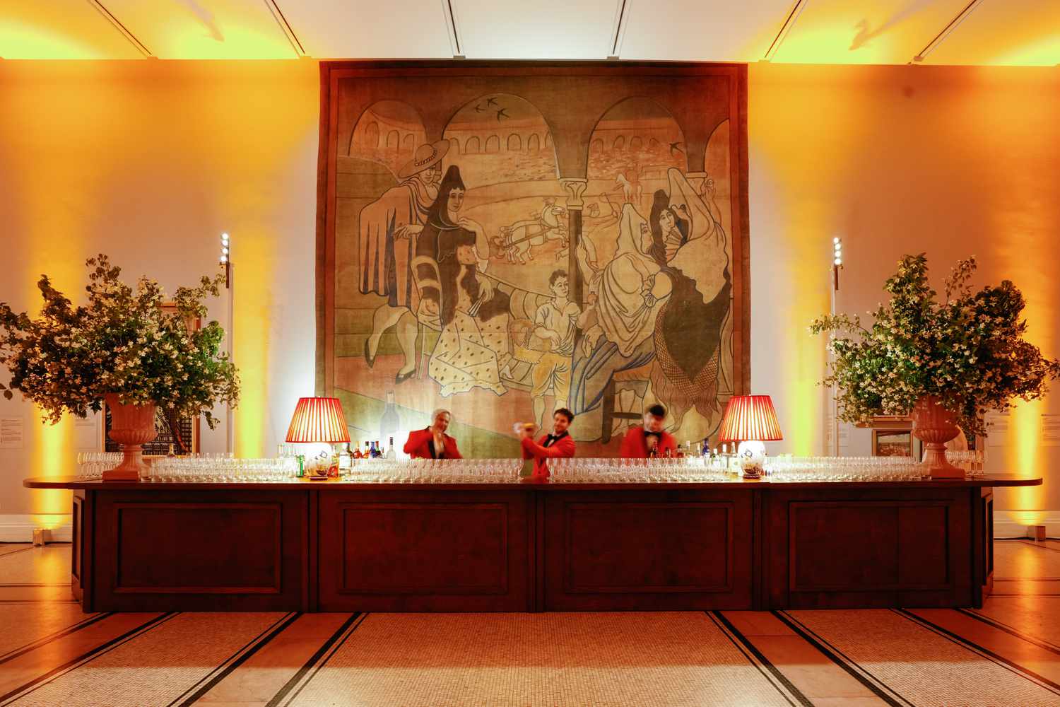 Wooden Bar With Orange Lamps and Oversized Flowers and Orange Uplighting