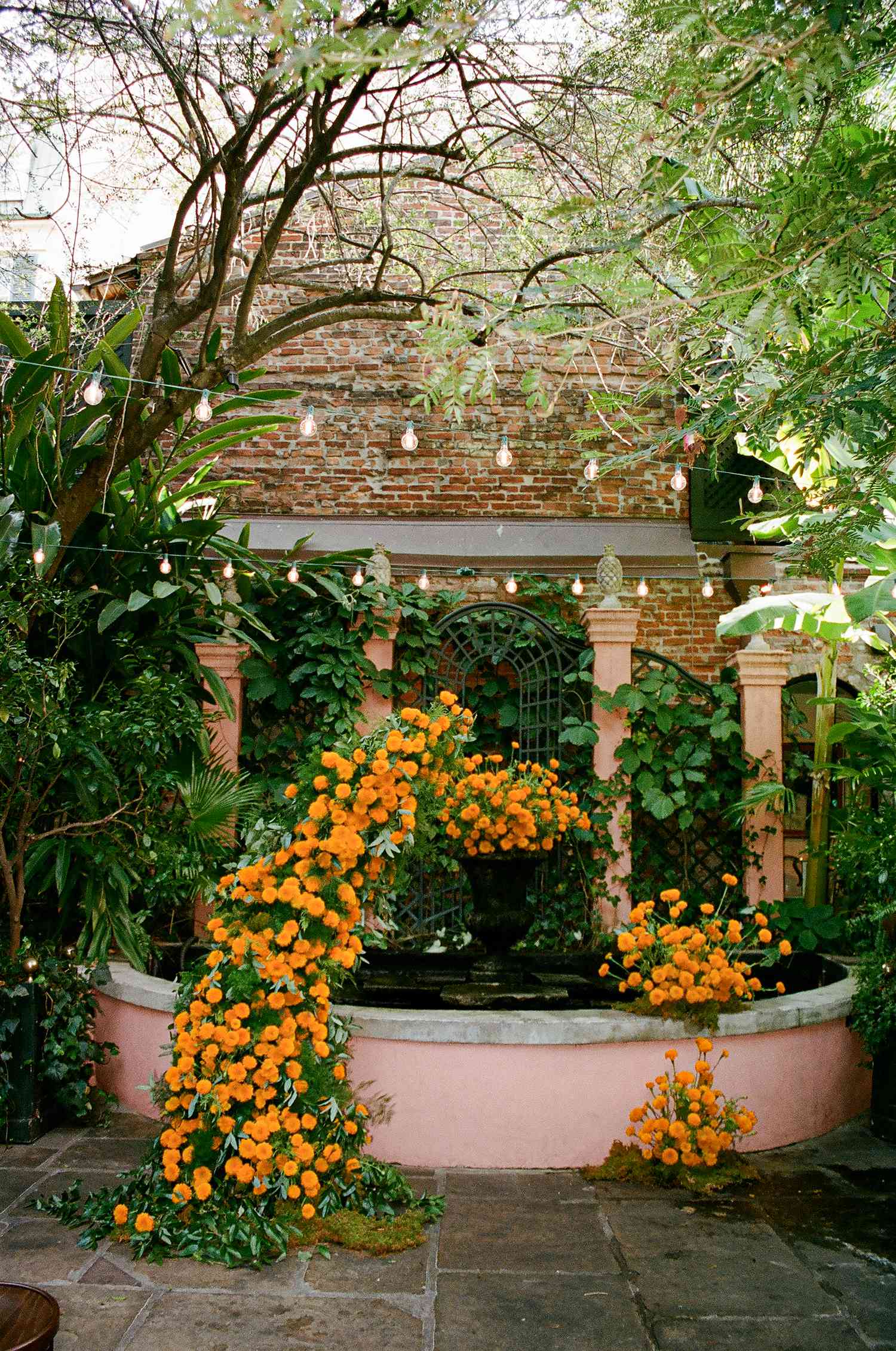 Orange Floral Installation Along Fountain Outside in Garden