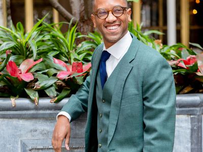 Groom wearing a three-piece teal suit, a navy blue tie, and glasses