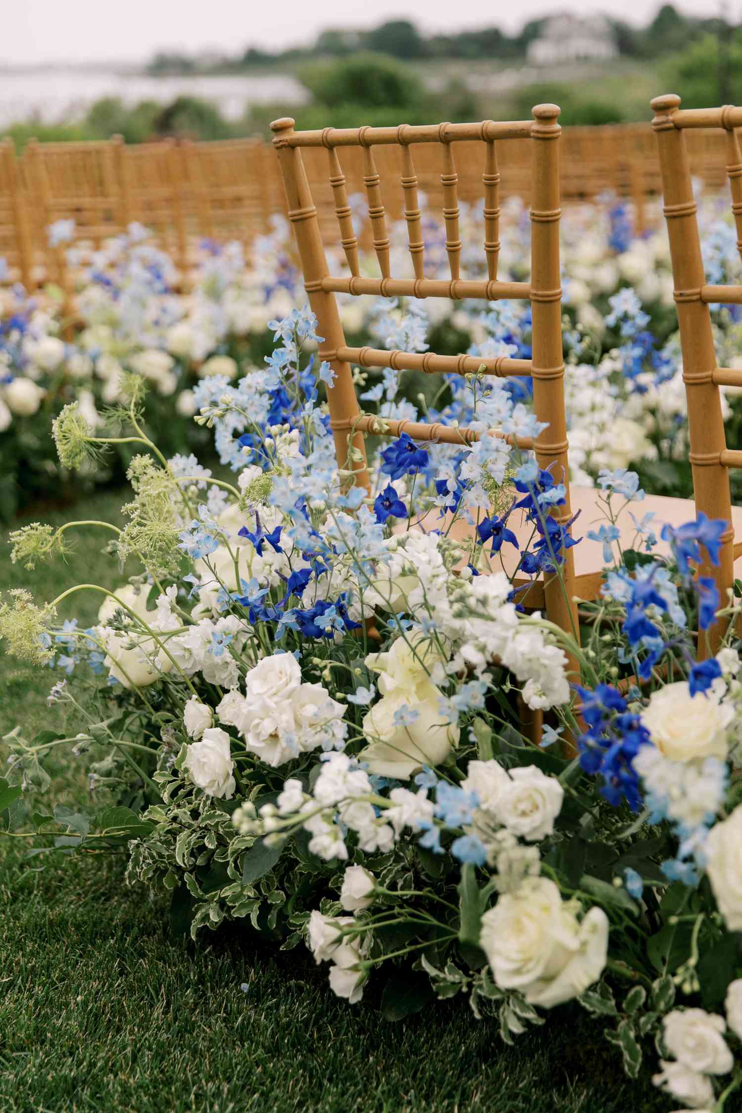 Blue and white floral arrangements along wooden chiavari chairs