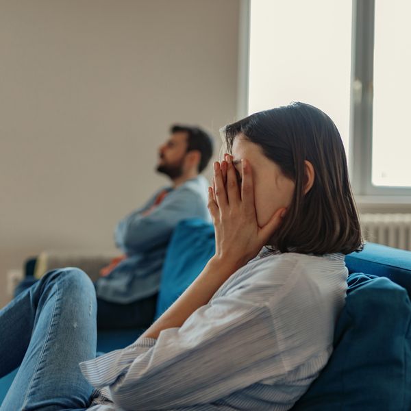 Unhappy Couple Sitting on a Couch Fighting, Young Woman With Short Hair Covering Face with Hands