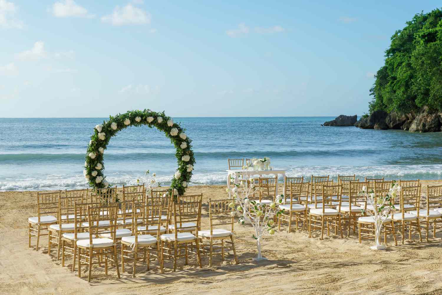 Beachside wedding ceremony with white chairs and floral altar overlooking the ocean in Jamaica