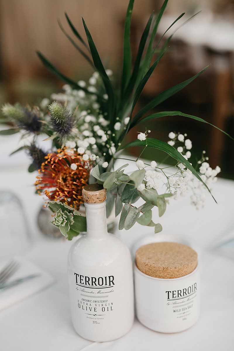 Bottles of Olive Oil Next to Greenery Centerpieces on White Tablecloth