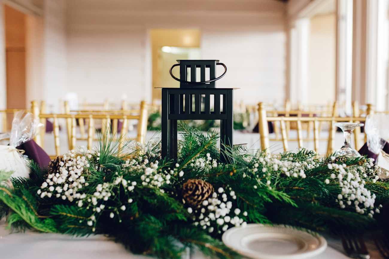 black lantern with pine cones and boughs on winter tablescape