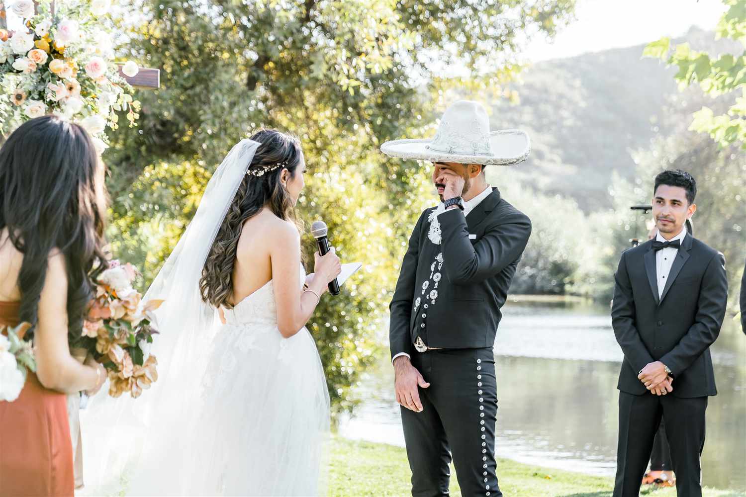bride reciting vows while holding microphone while groom in sombrero wipes away tears