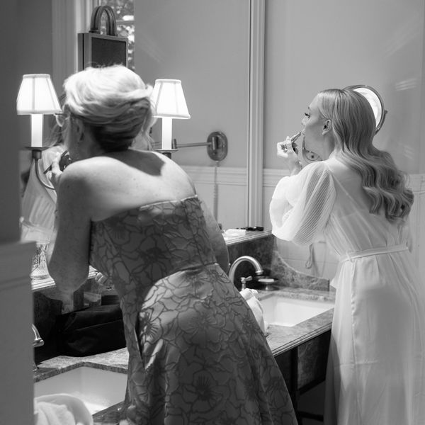 Bride Does DIY Wedding Makeup in The Mirror Before Ceremony Next to Her Mom