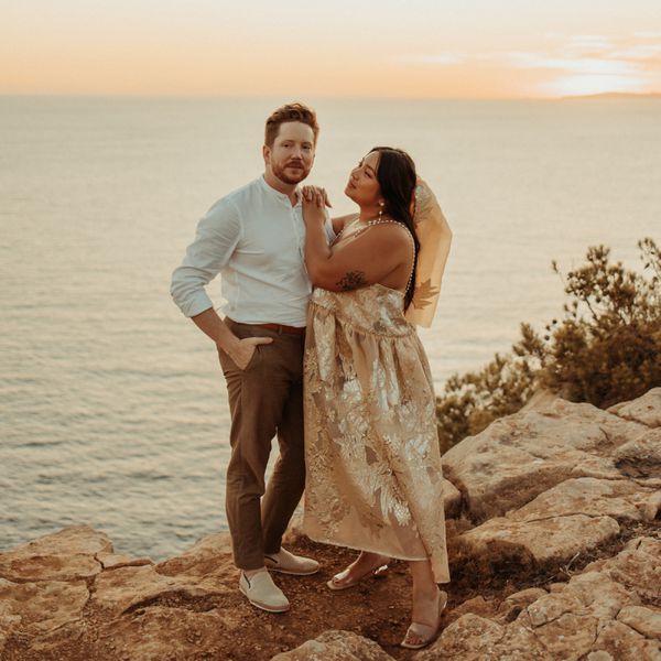 Couple Standing on Cliff Overlooking the Ocean at Sunset