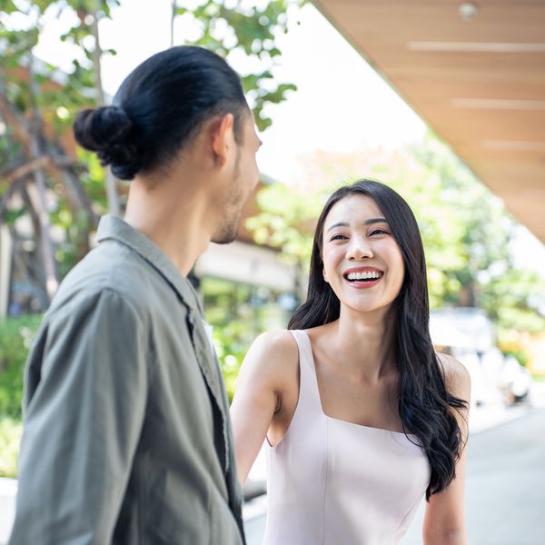 Asian Woman Laughing While Looking at Man Outside
