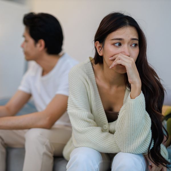 Brunette Woman Looking Concerned on the Couch With a Man Looking Off in the Background