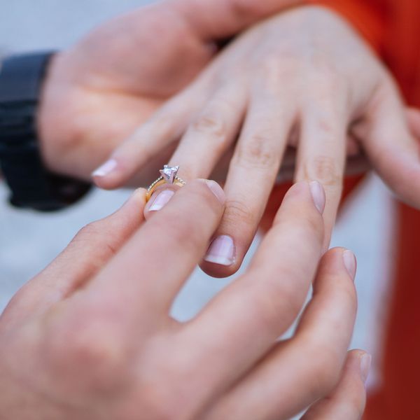 Man Slides Engagement Ring Onto Woman's Finger 