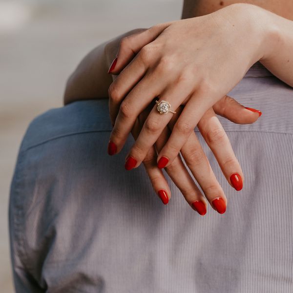 Woman With an Engagement Ring and Red Nails Embraces Her Partner
