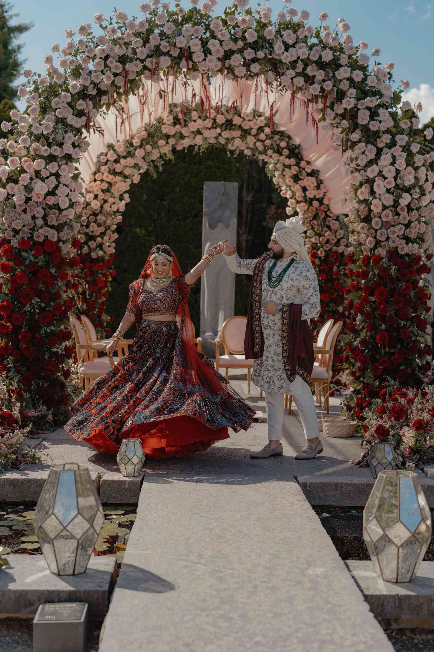 groom spinning his bride under two floral arch mandaps