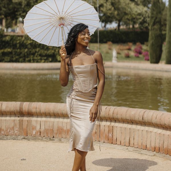 wedding guest wearing a two piece being cocktail dress holding a parasol