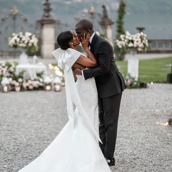 Bride and groom kissing outside with blurred floral assortments in the background