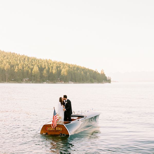 Bride and groom kissing on a boat with with an American flag on a lake