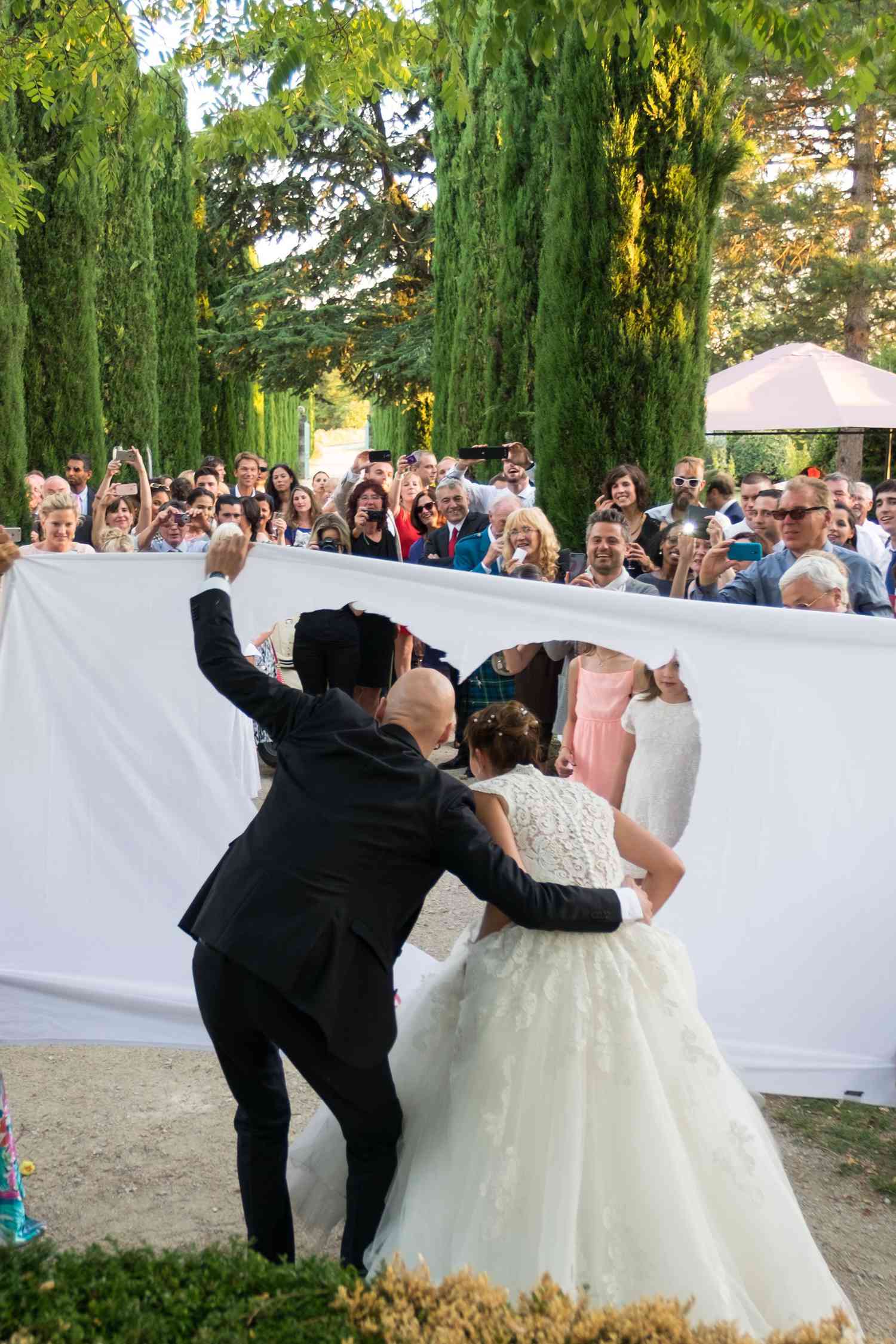 newlyweds walking through a white sheet with a heart cutout