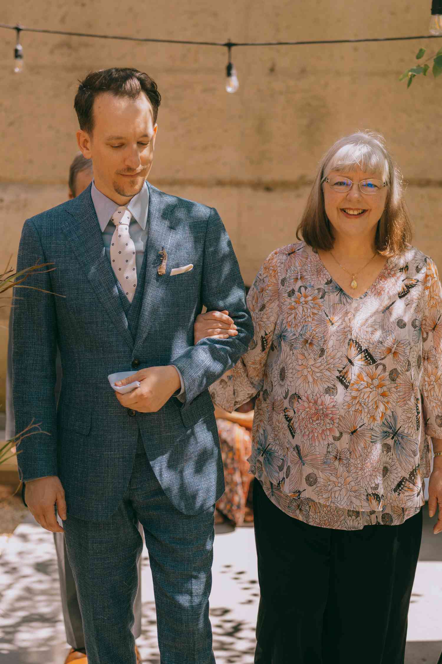 groom walking down the aisle with his mom