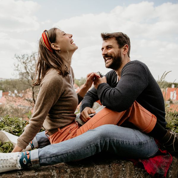 happy couple sitting outdoors on a beautiful day flirting on the fence