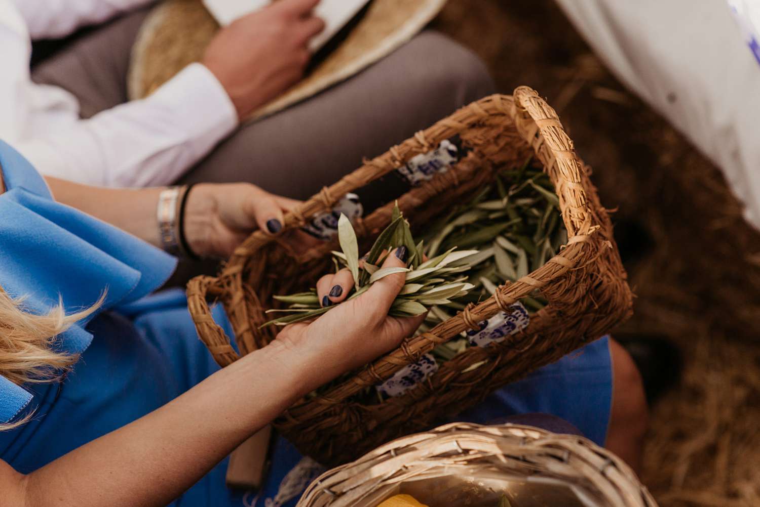 Wedding guest grasping Olive leaves in woven basket
