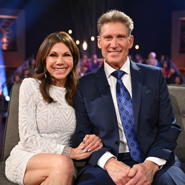 Theresa Nist and Gerry Turner smiling while sitting on a couch in front of a live studio audience