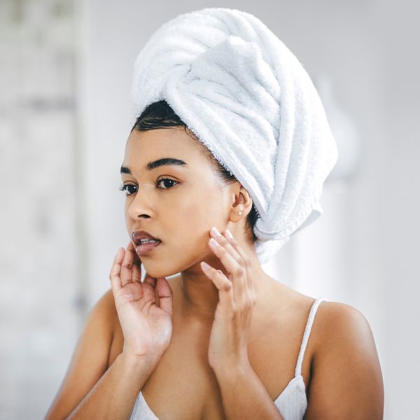 Young woman going through her morning beauty routine looking into a mirror