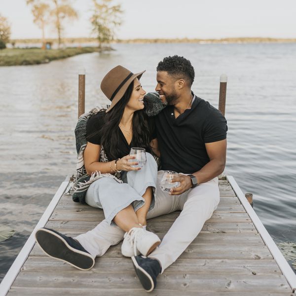 couple in matching outfits sitting on dock smiling at each other