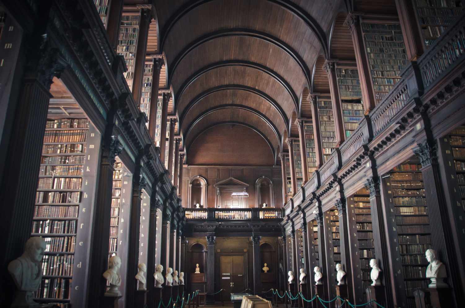 Interior view of wood-paneled rooms with shelves of books at Trinity College Library in Dublin, Ireland.