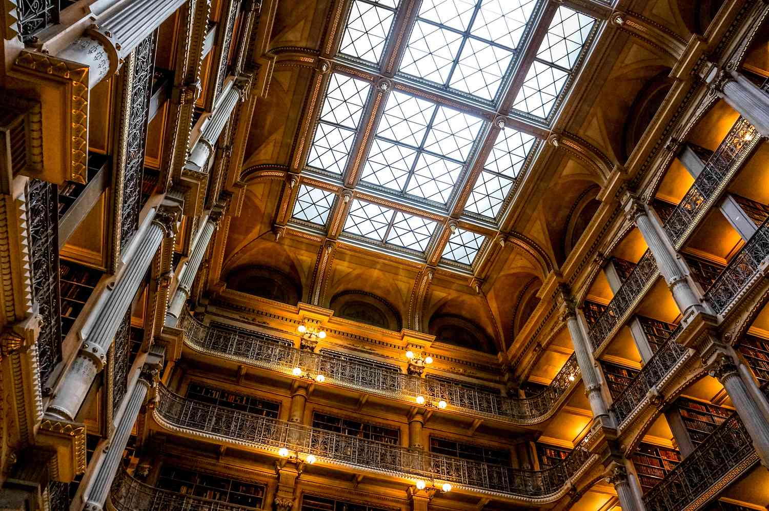 A view of the floors of books, dimly lit by lanterns and a skylight, at the George Peabody Library in Baltimore.