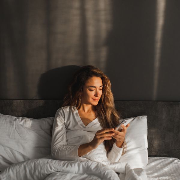 woman texting on her cell phone in bed