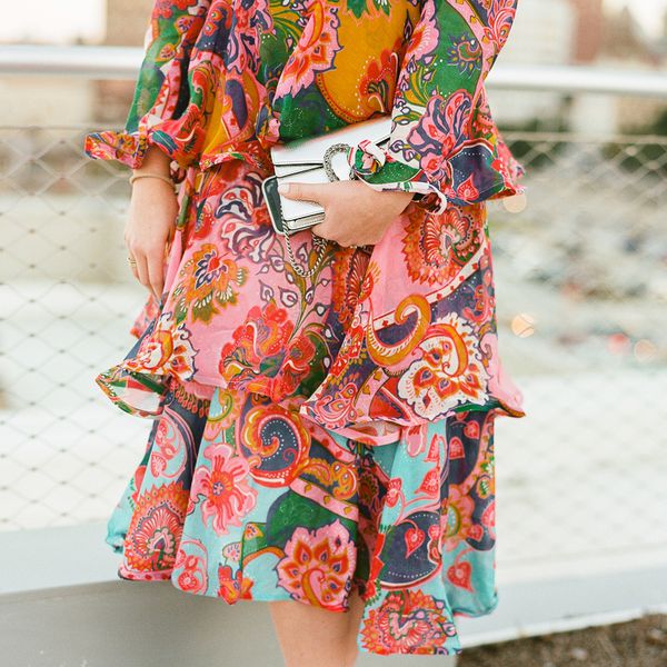 wedding guest wearing a printed ruffle dress and holding a silver clutch