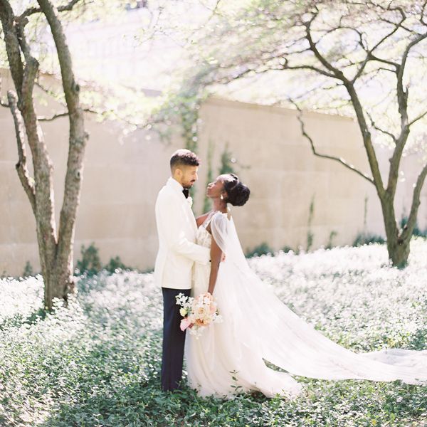Portrait of Groom in White Tuxedo Jacket and Bride in Off-the-Shoulder Wedding Dress in a Field of Greenery
