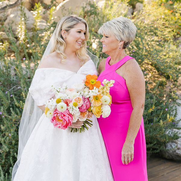 Bride in Off-the-Shoulder Wedding Dress Smiling at Mother of the Bride in Hot Pink Halter Neck Gown