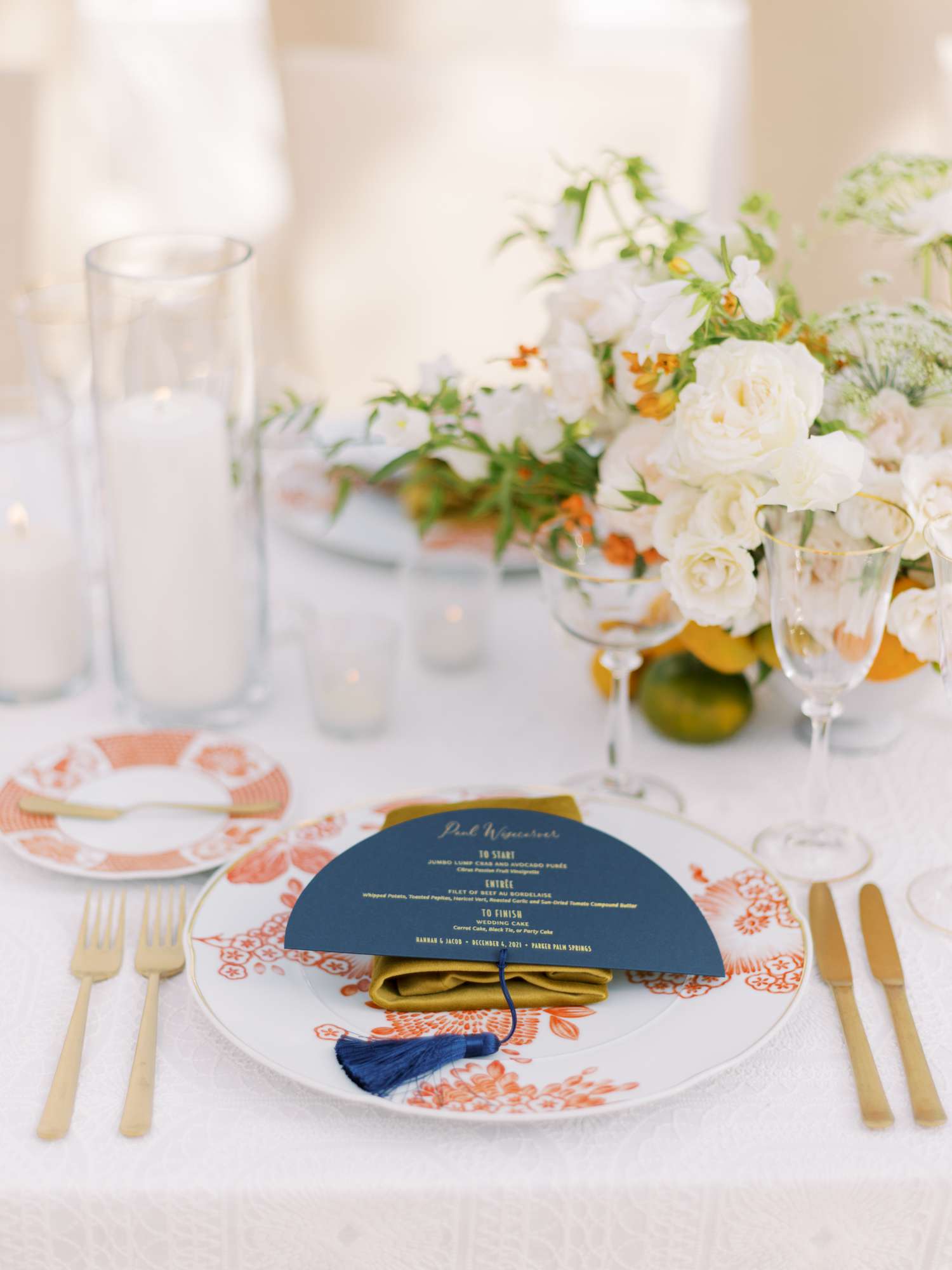 Wedding tablescape with orange and white printed plates and navy menu card