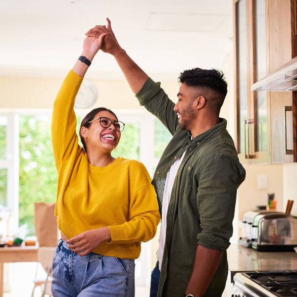 Happy Young Couple Smiling While Dancing in the Kitchen