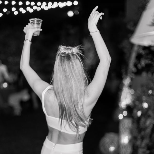 Bride Dances With a Drink and Her Hands in the Air During a Hen Do