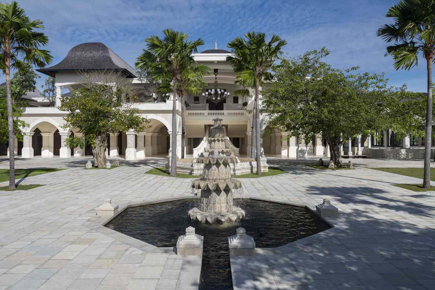 Tall palm trees line the stone entrance of Jumeirah Bali
