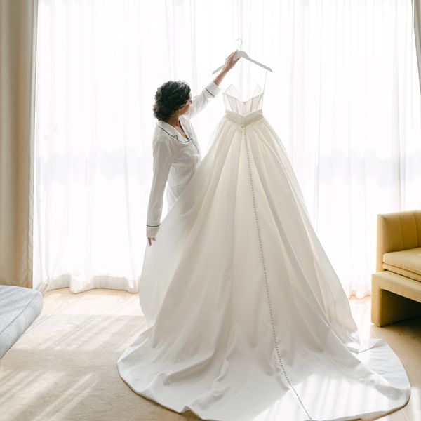 bride holding up her wedding gown on a hanger