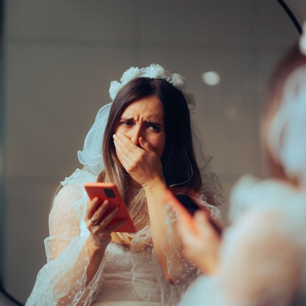 Horrified Bride Looks at Phone While Covering Face on Wedding Day