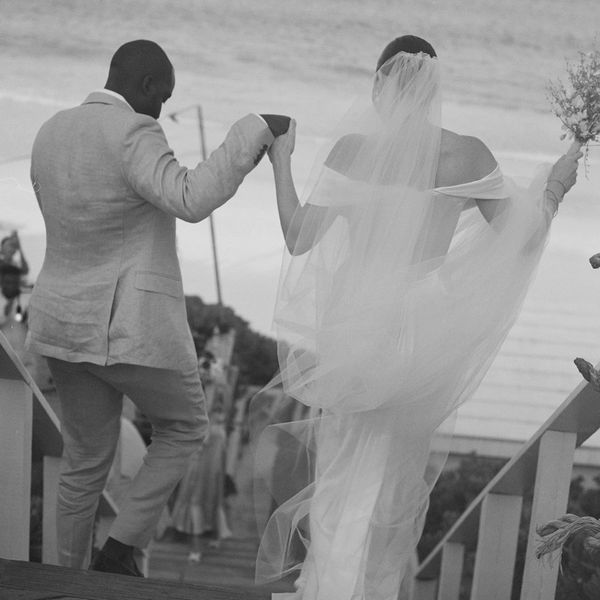 bride and groom holding hands and walking towards ocean