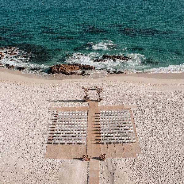 beach wedding setup with rows of chairs and arch