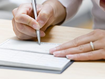Woman Writing a Wedding Check on Wood Table