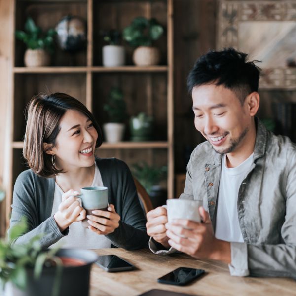 Happy young couple having a coffee date in cafe, drinking coffee and chatting.