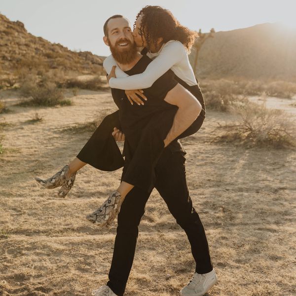 man with beard carrying woman with curly hair on his back