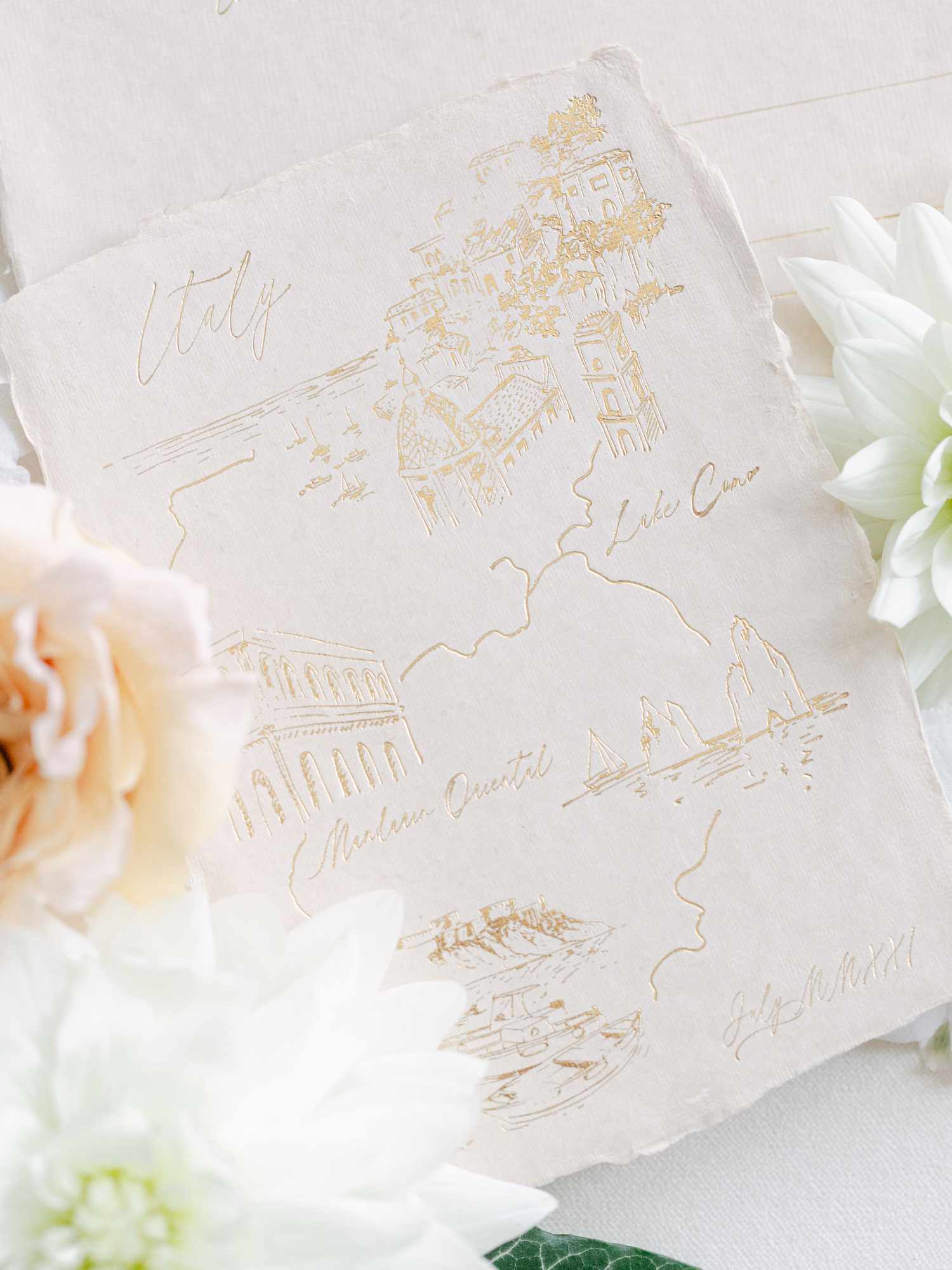 A deckle-edge wedding invitation with gold embossed illustrations. 