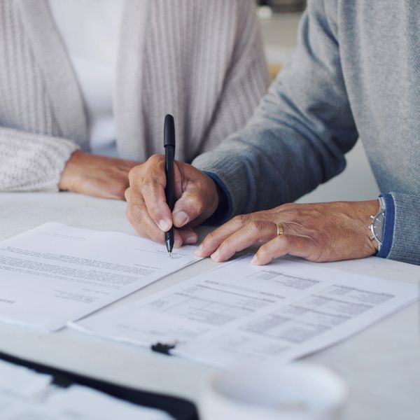 Closeup of Man Signing Papers With Woman Sitting Next to Him